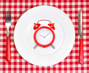 Diet lunch  time concept.Red alarm clock on round white plate.