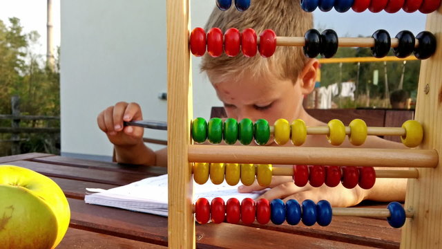 Little boy doing homework outside on terrace