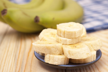 green banana with slices on wooden background