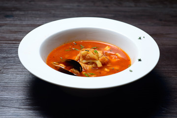 Delicious soup with mussels on black background