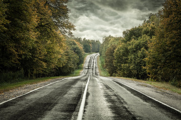 Dark asphalt road under a storm sky