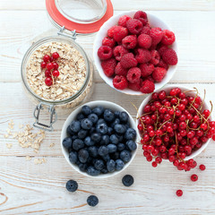 Breakfast - berries, fruit and muesli on white wooden
