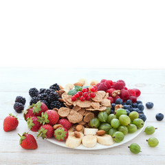 Breakfast - berries, fruit and muesli on white wooden