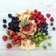 Breakfast - berries, fruit and muesli on white wooden