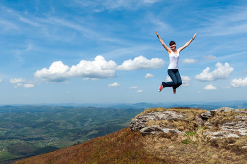 young woman jumping on a background of mountains