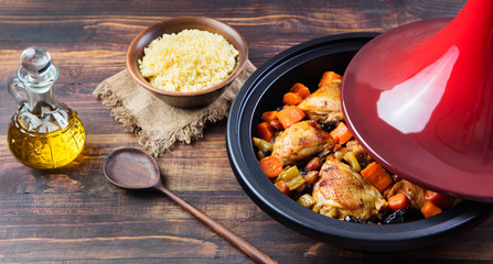 Tagine with cooked chicken and vegetables Wooden background Copy space
