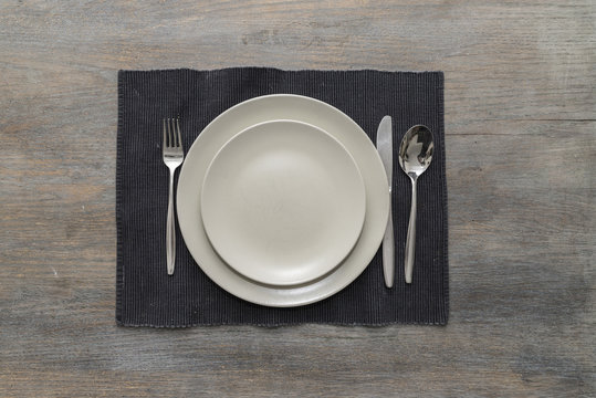 Two off-white plates with fork, knife and spoon on a black place