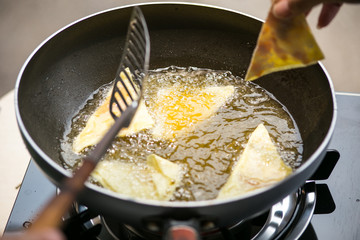 Dough sheet deep frying in very hot oil.