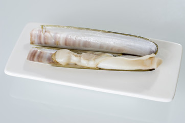 White dish of grilled razor clams with lemon