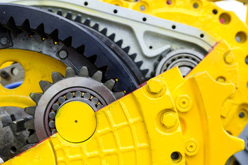 Drive gear and bearings, cross section of bulldozer sprocket internal mechanism, large construction machine with bolts and yellow paint coating, heavy industry, detail 