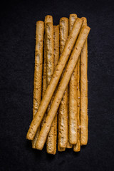Bread sticks with salt and herbs on dark board
