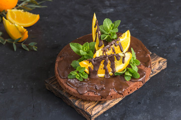 Chocolate cake with chocolate frosting and orange slices,mint. Flowers