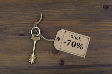 Key and a note on a wooden table with text - Sale