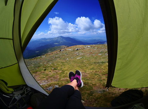 Woman lying in a tent with coffee ,view of mountains and sky