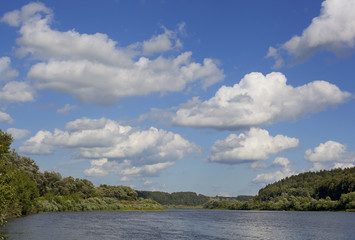 Summer landscape with river and clouds over the water.
