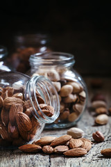 Almonds in jars on a dark wooden background, selective focus