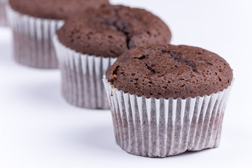 Brown chocolate muffins arranged over white background