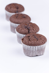 Brown chocolate muffins arranged over white background