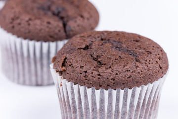 Brown chocolate muffins arranged over white background