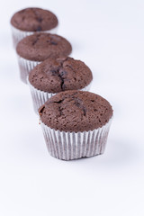 Brown chocolate muffins arranged over white background