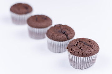 Brown chocolate muffins arranged over white background