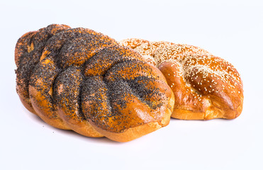 Two whole fresh challah bread with poppy and sesame seeds on a w