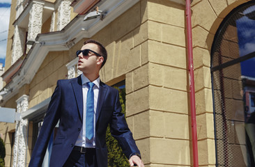 Stylish businessman in the sunglasses near building