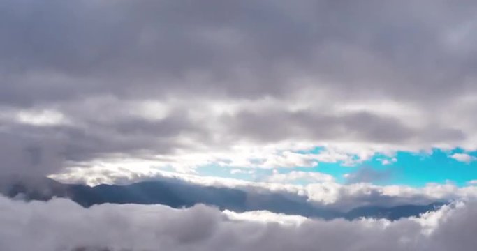 Amazing aerial view above clouds with sun light rays and distant mountain
