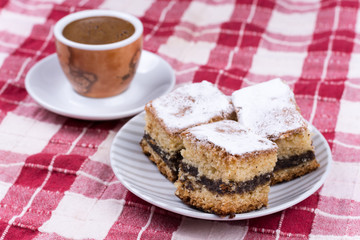 Cup of coffe with cakes on the plate over red and white tableclo