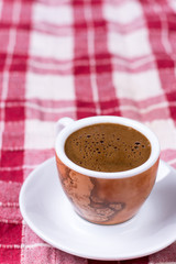 Cup of coffee over red and white tablecloth