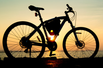 Fototapeta premium Silhouette of mountain bike at sea with sunset sky background