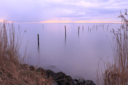 zonsopkomst boven een verstild Markermeer met doorkijkje op fuiken