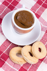 Cup of coffee with round tea cookies on the tablecloth
