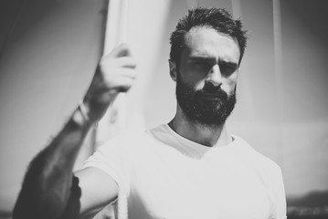 Obraz premium Portrait of young bearded man standing on the yacht in sunny day. Horizontal mockup, black and white