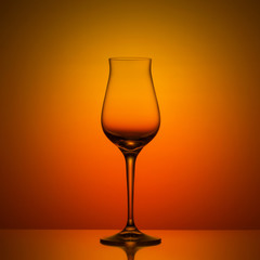 Empty wineglass on orange background