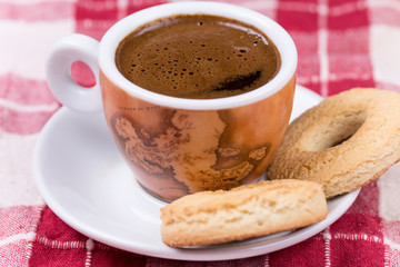 Black coffee with round tea cookies on the plate
