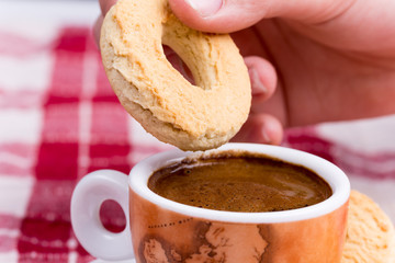 Hand dipping round cookie in to coffee cup