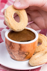 Hand dipping round cookie in to coffee cup