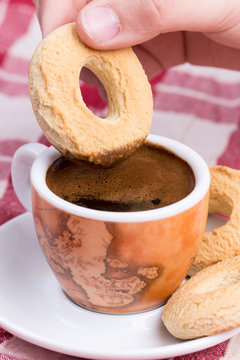 Hand dipping round cookie in to coffee cup