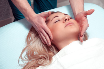 Fototapeta na wymiar Masseur doing massage the head of an adult woman in the spa salo