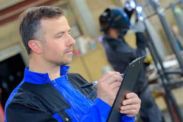 Workman making notes on clipboard