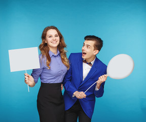 Smiling hipster couple in the jeans and jacket with the sheet and balloon in the studio
