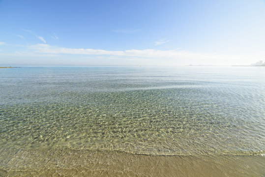 Crystal clear turquoise water at La Manga del Mar Menor beach in Murcia Spain. Beach  with white sand and turquoise water under blue sky