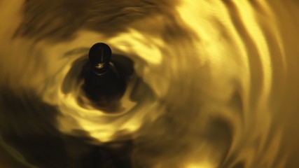 Orange Water Drop - A high quality, super slow motion in camera macro shot of a single orange water drop falling into frame, producing silky waves and ripple effects. - Powered by Adobe