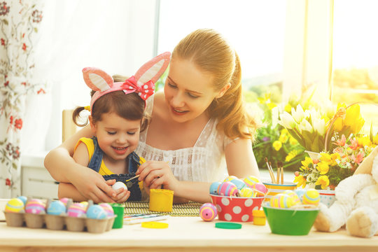 happy family mother and child girl paints eggs for Easter