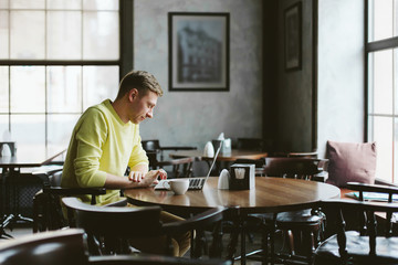 Happy man working at a laptop in cafe