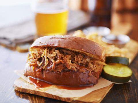 Pulled Pork Sandwich On Wooden Tray With Pickles And Beer