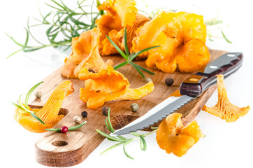 Chanterelle mushrooms with rosemary and pepper seeds on wooden b