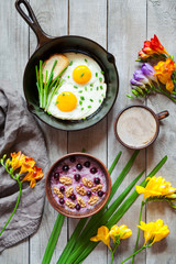 Healthy diet breakfast with spring morning mood, oatmeal porridge with nuts and blackberry, coffee and fried eggs in cast iron skillet on vintage wooden background. Top view