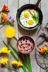 Healthy nutrition breakfast with fried eggs, juice, and oatmeal with nuts and blackberry.  Spring morning mood on vintage wooden background. Top view